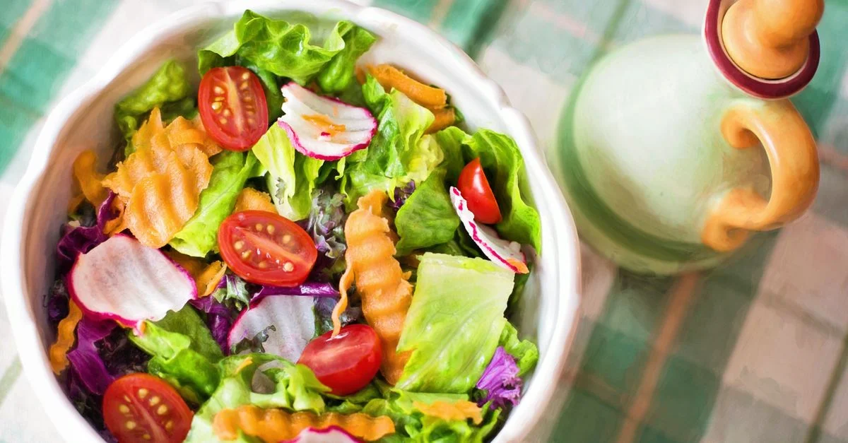 Salade de légumes frais colorés avec des tomates cerises dans un bol blanc.