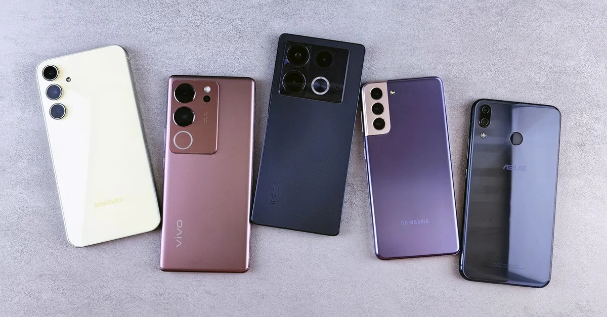 Vue de dessus de cinq smartphones modernes sur une surface grise, présentant différents designs.