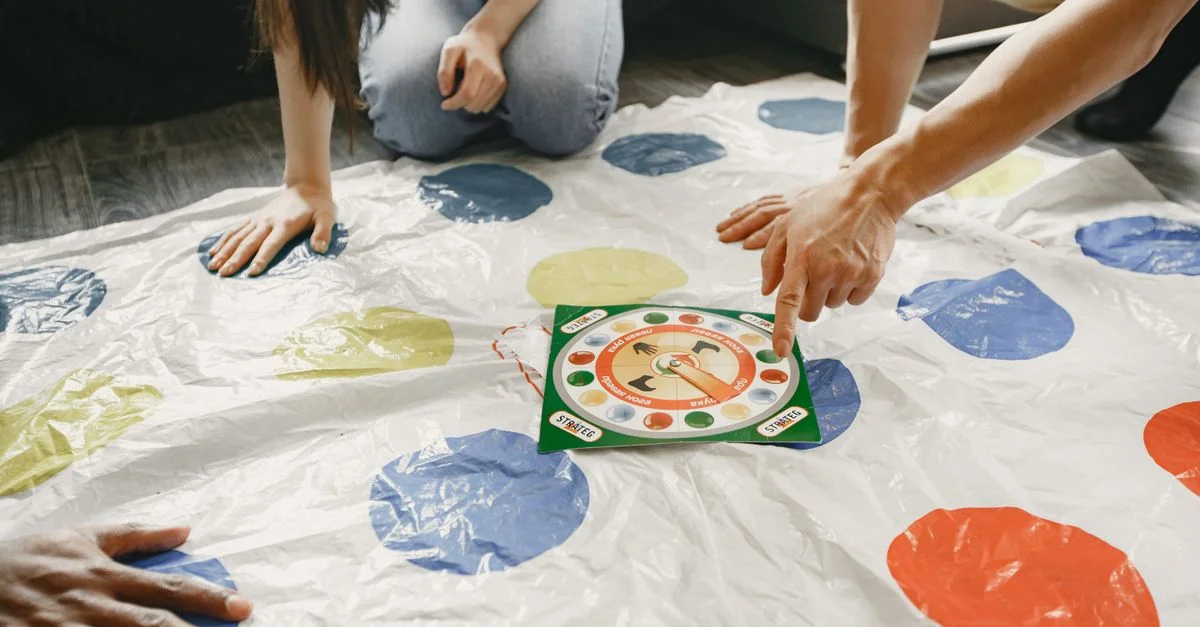 Des mains sur un tapis coloré avec un plateau tournant au centre. Un jeu amusant et interactif.