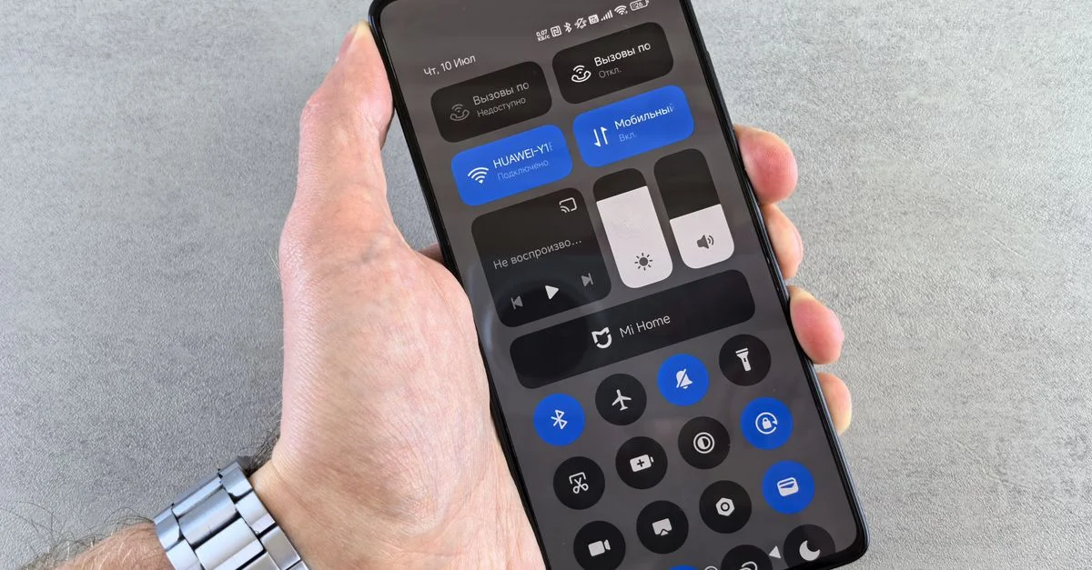 Gros plan d'une main tenant un smartphone affichant son interface de panneau de contrôle.